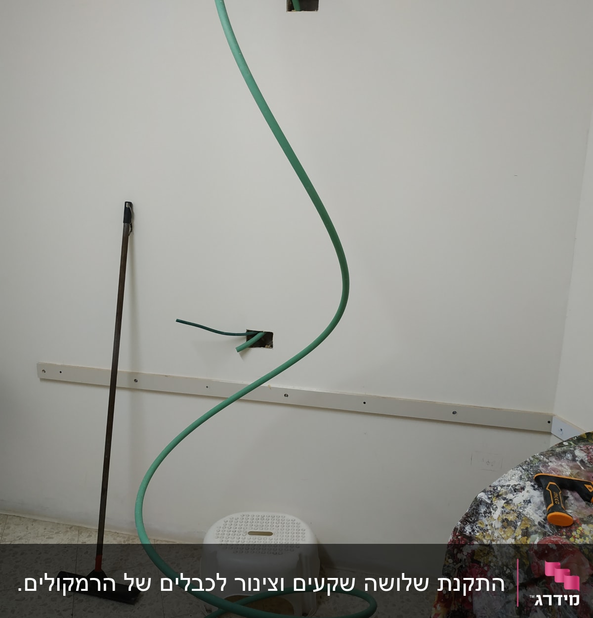 צינור ירוק יוצא מקיר עם כלי עבודה